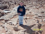 Duncan stands in a T-Rex track, outlined by small rocks.